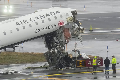 Officials investigate the site, Monday, March 23, 2026, where an Air Canada jet came to rest after colliding with a Port Authority firetruck at LaGuardia Airport, shortly after landing Sunday night in New York. 
