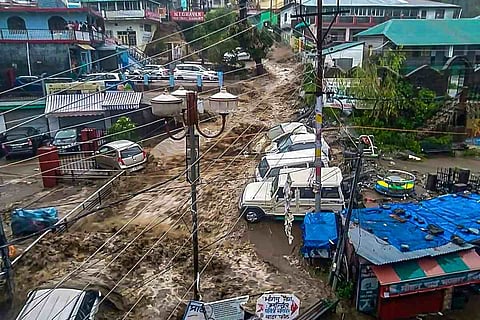 Flood water surges through a street amid heavy rain after a cloudburst, at Mcleodganj near Dharamshala, Monday, July 12, 2021.