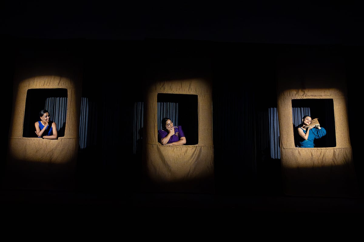 Image of three women enclosed within a window frame on stage