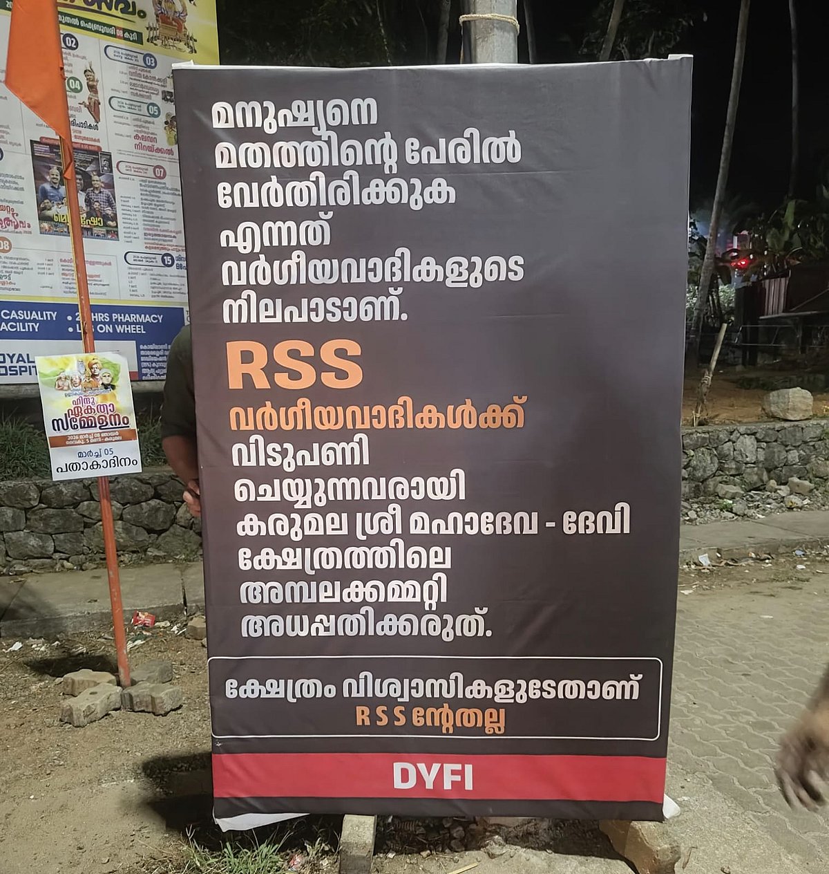 A DYFI poster displayed on a roadside criticising the RSS and opposing the Hindu Ekta Sammelanam organised at the Karumala Sree Mahadeva–Devi temple in Kozhikode.