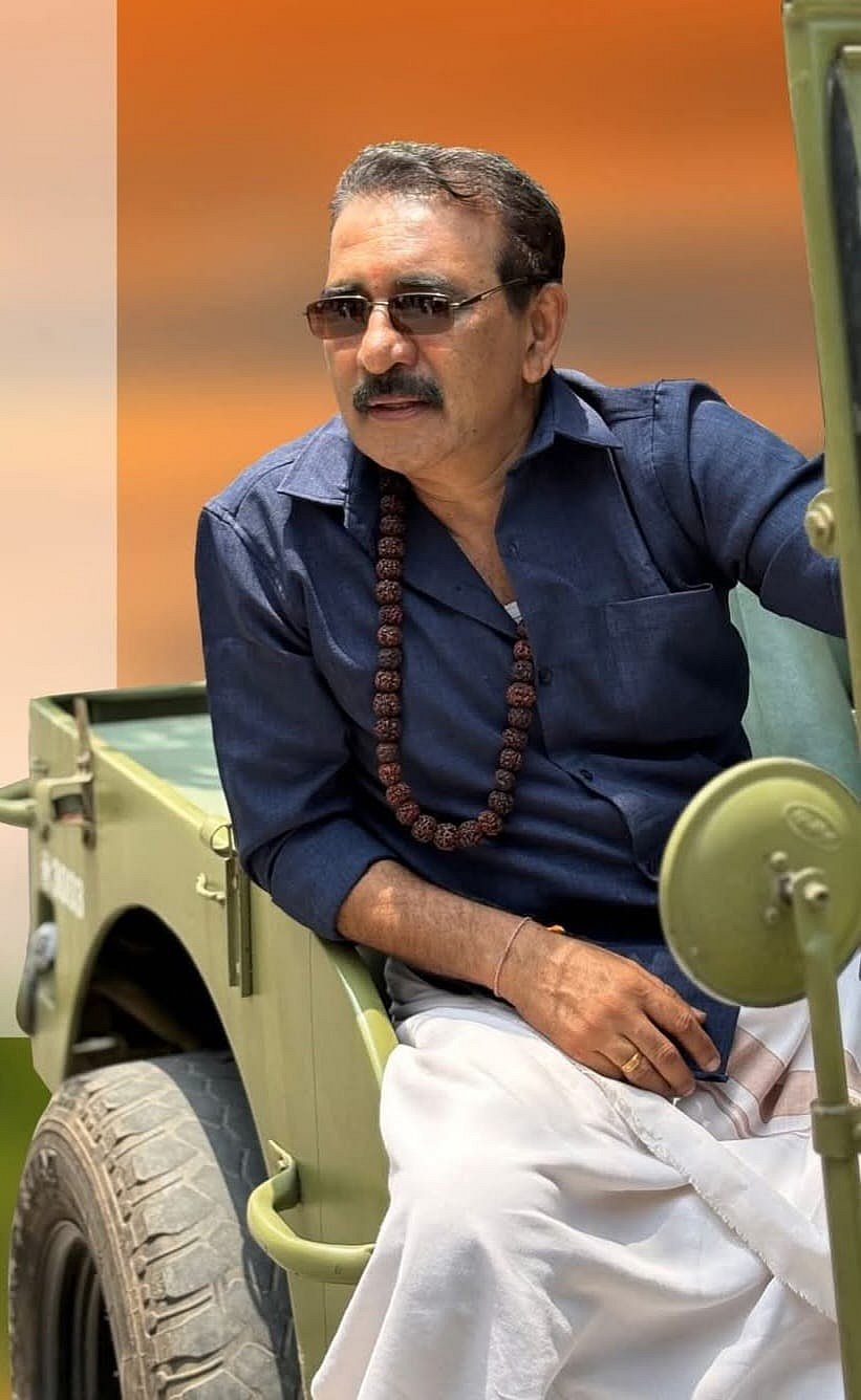 BJP candidate B Gopalakrishnan sitting on a jeep, wearing a dark shirt, white mundu, sunglasses, and a rudraksha bead necklace.