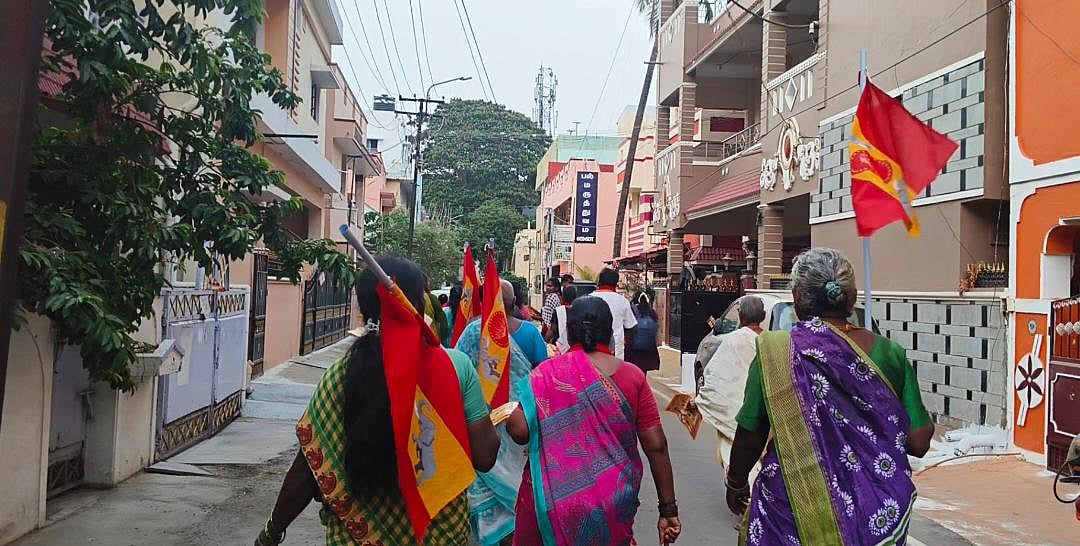 A group of women walking, holding TVK flags