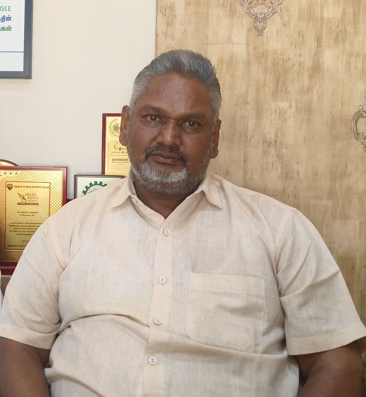 Abdul Hakkim in a light pink shirt, seated 