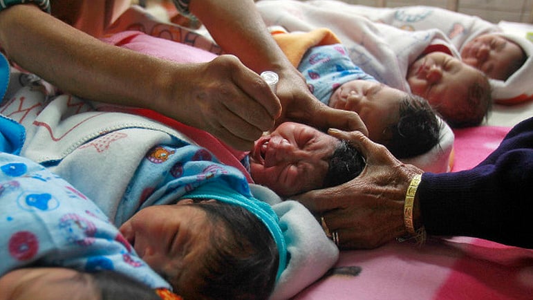 A medical worker administers polio drops to an infant at a hospital. 