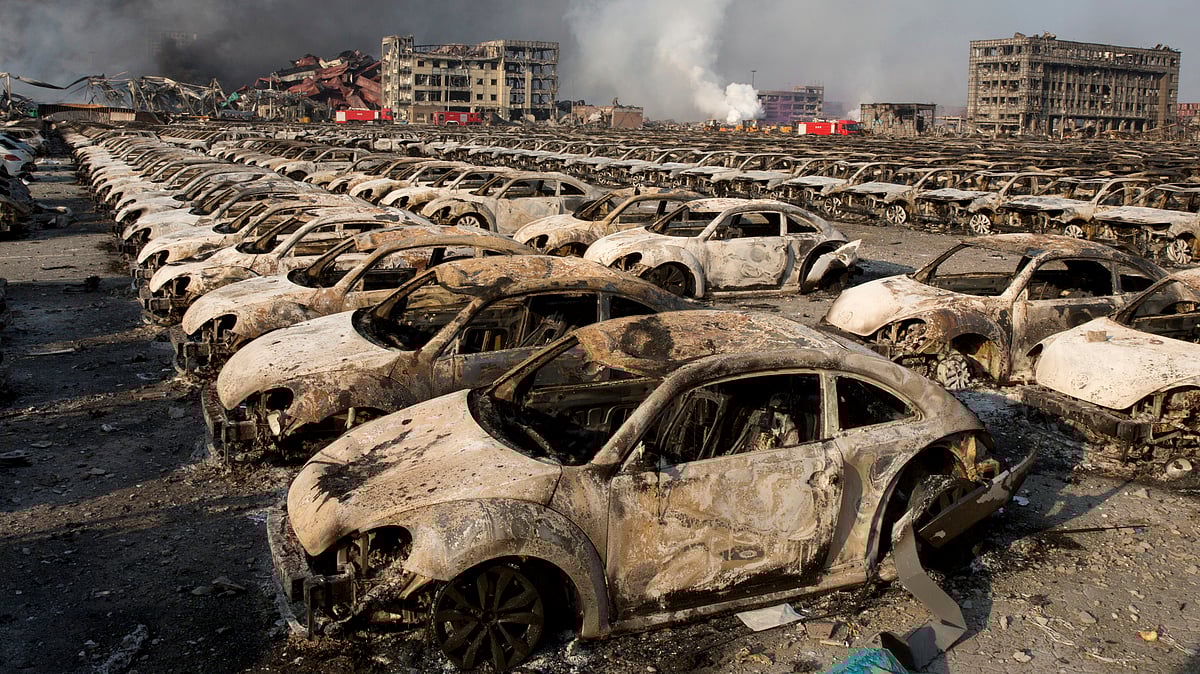 In this Aug. 13, 2015 photo, smoke rises from the site of an explosion that reduced a parking lot of new cars to charred remains at a port warehouse in north-eastern China’s Tianjin municipality. (Photo: AP)