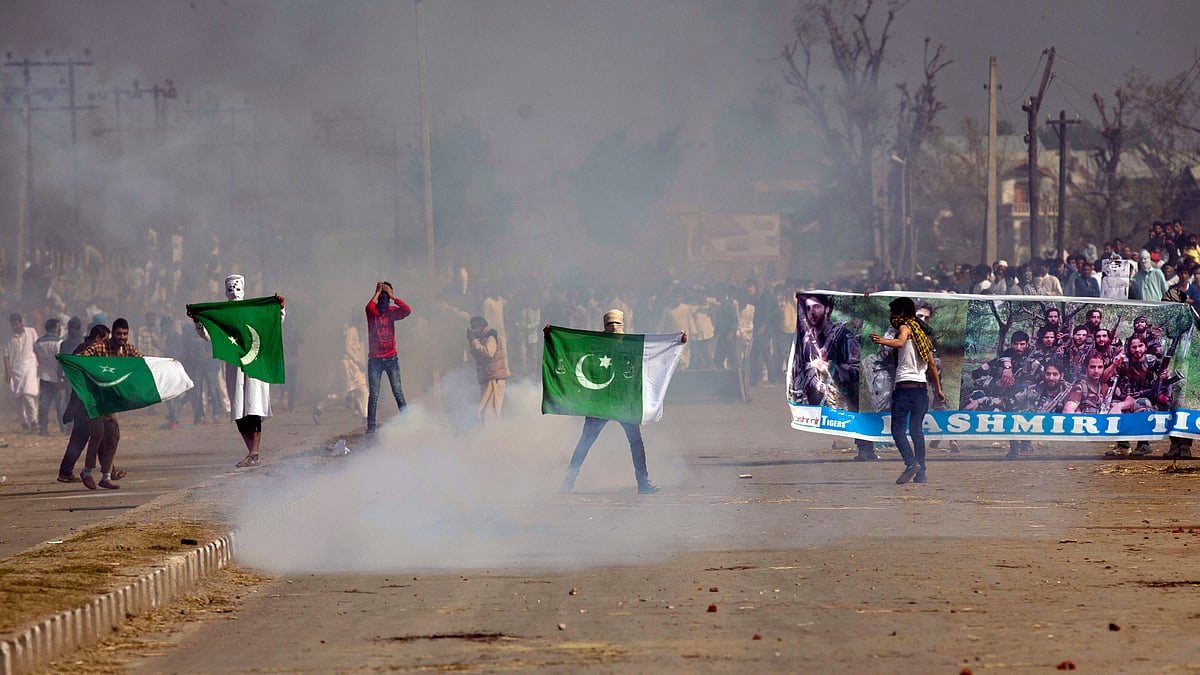 Masked Kashmiris hold the national flag of Pakistan and a banner displaying militant leaders of the Hizb-ul Mujahedeen during a protest. (Photo: AP)