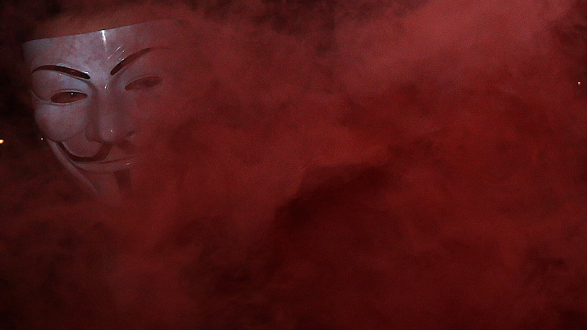 A supporter of the activist group ‘Anonymous’ holds a flare during a protest in London. (Photo: Reuters)