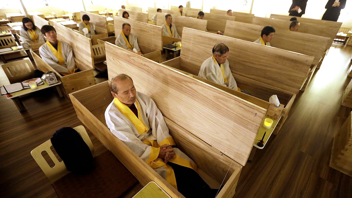 Wang Yong-yo, left bottom, sits inside a wooden coffin during the “death experience” program at Hyowon Healing Center in Seoul, South Korea, Tuesday, December 22, 2015. (Photo: AP)