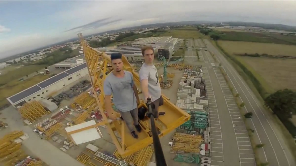 This daring duo make their way along the unsteady crane with NO safety equipment. (Photo: AP screengrab)