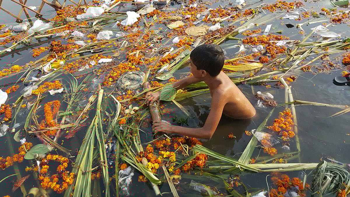 A boy wades through a canal near Kalyanpuri with the remains of the recently held Chhath Puja. (Photo: <b>The Quint</b>)