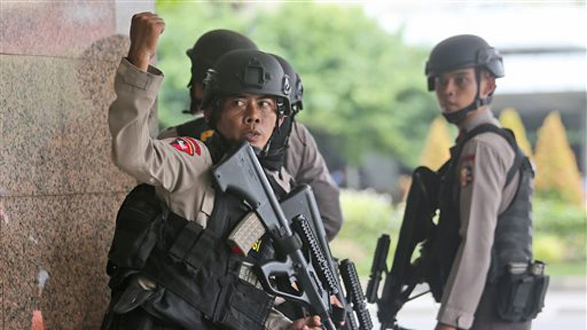 A police officer gives a hand signal to a squad mate as they search a building near the site of an explosion in Jakarta. (Photo: AP)