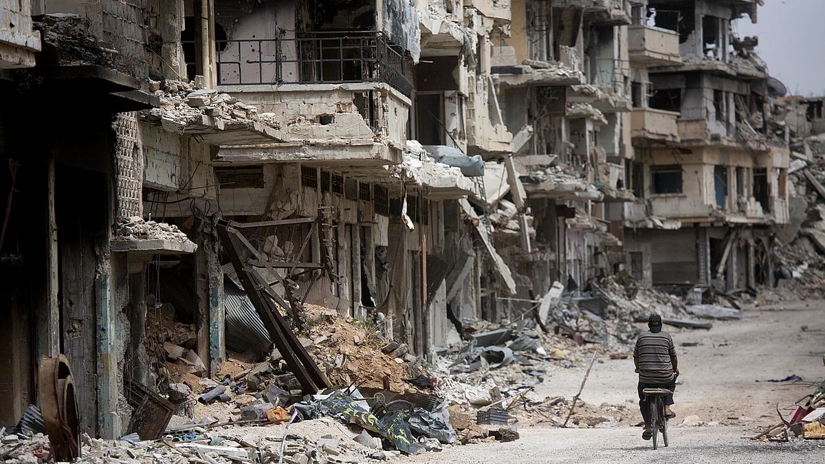 

A man rides a bicycle through a devastated part of Homs, Syria. (Photo: AP)