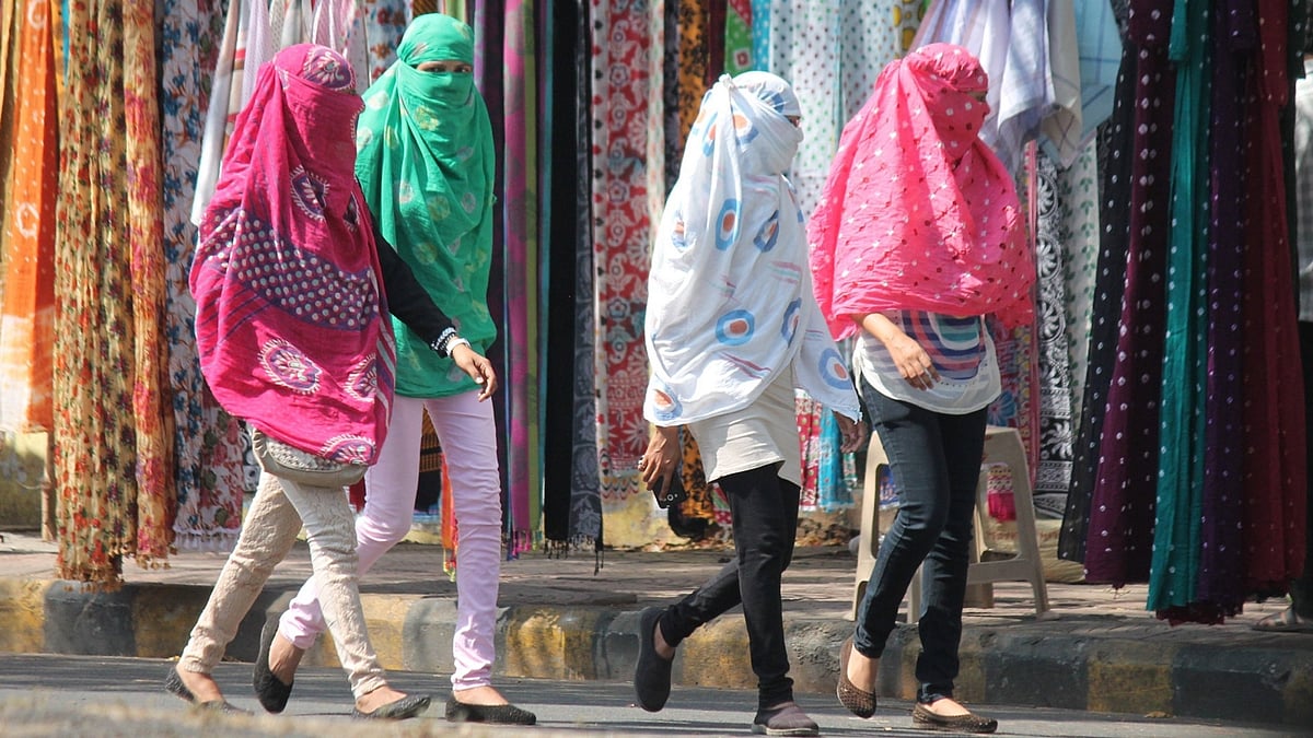 Women cover their faces to avoid direct contact with sun on a hot day. (Photo: IANS)
