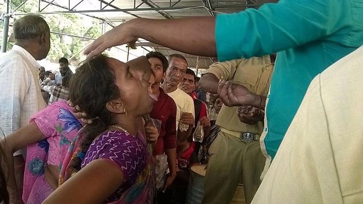 People look on as a woman eats  live fish ( Photo Courtesy: <i>The News Minute</i>)