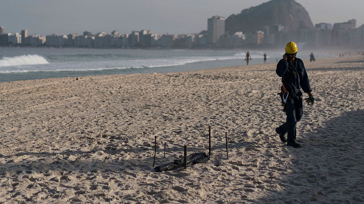 A construction worker of the Olympic beach volleyball venue observes a dismembered human foot covered with black plastic after it was found in front of the venue in Copacabana beach in Rio de Janeiro, Brazil.(Photo: AP)<a></a>