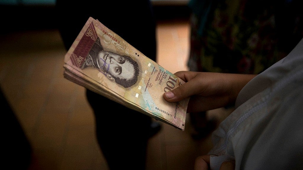 

A customer holds a stack of 100-bolivar notes at a bakery in downtown Caracas, Venezuela, Monday 12 December 2016. Venezuelans are rushing to spend their 100-bolivar notes after a surprise announcement that they will be taken out of circulation this week. (Photo: AP)
