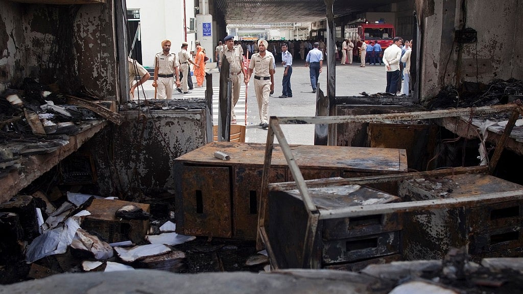 A file image of police and private security guards walking past damaged reception block of Maruti Suzuki’s plant in Manesar in July 2012. (Photo Courtesy: Reuters)