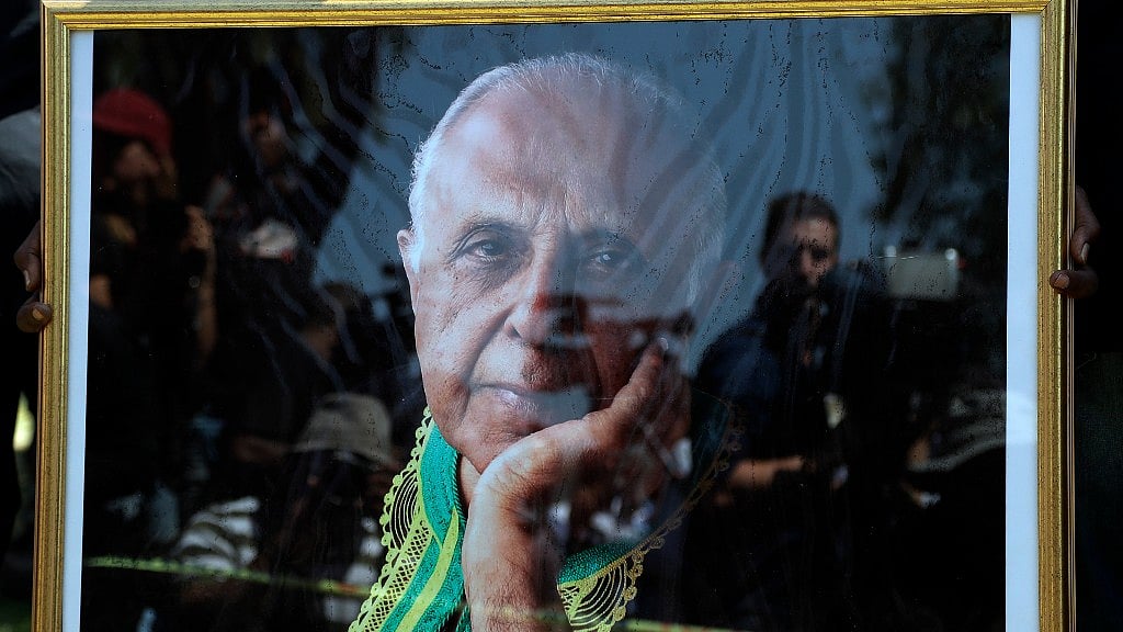A mourner holds a portrait of Ahmed Kathrada, at West Park Cemetery in Johannesburg, South Africa on 29 March 2017. (Photo: AP)