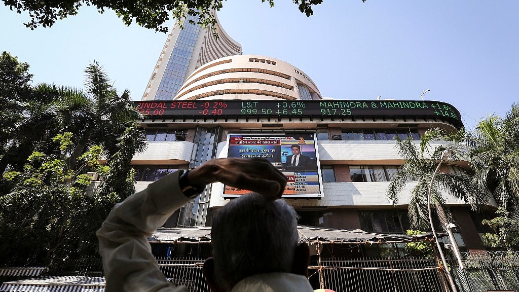A man looks at a screen across the road displaying the Sensex on the facade of the Bombay Stock Exchange (BSE) building in Mumbai. 