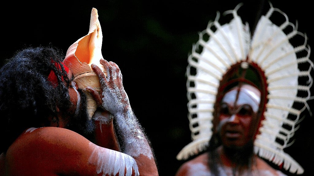 An Australian Aboriginal man blows into a shell while an indigenous man from the Torres Strait Islands wearing traditional dress performs during a welcoming ceremony at Government House in Sydney, Australia.