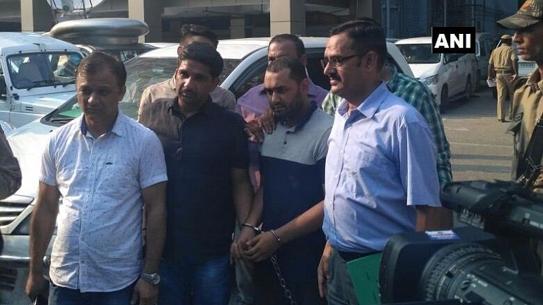The alleged Al-Qaeda militant  (in handcuffs) with security officials.