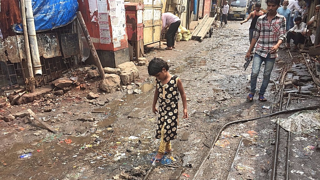 A child washes her feet in the water gushing out of a pipe meant to contain drinking water.