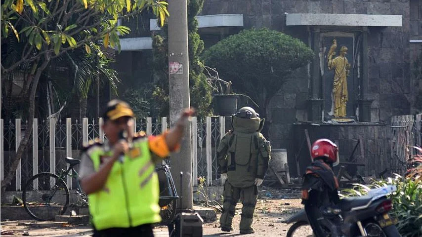 A member of the police bomb squad unit examines the site of an explosion outside the Immaculate Santa Maria Catholic Church, in Surabaya, East Java, Indonesia.