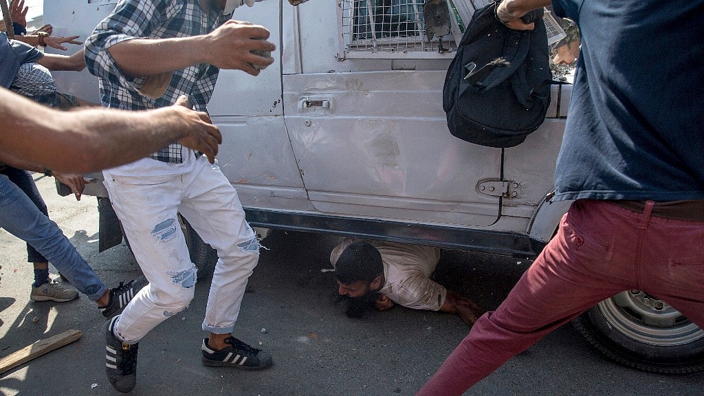 People gather around a paramilitary vehicle as it runs over a man during a protest in Srinagar, 1 June, Friday. 