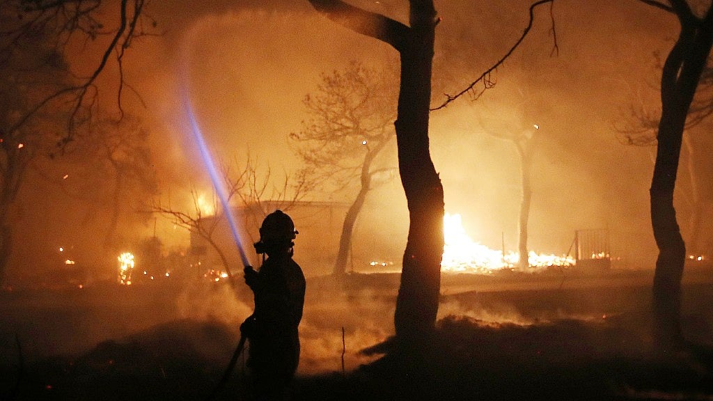 A firefighter sprays water on the wildfire in the town of Mati, east of Athens,  July 23, 2018.