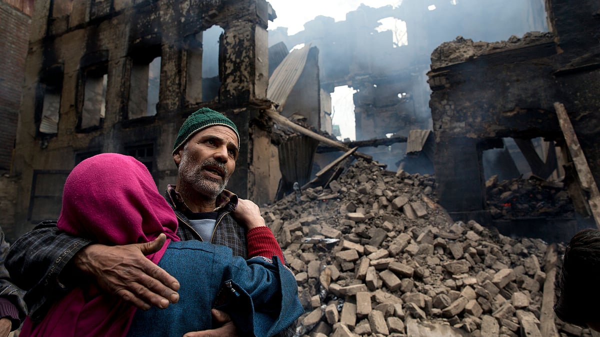 A Kashmiri woman comforts a wailing relative after his house was destroyed in a gunbattle in Tral village, south of Srinagar, on Tuesday, 5 March.&nbsp;