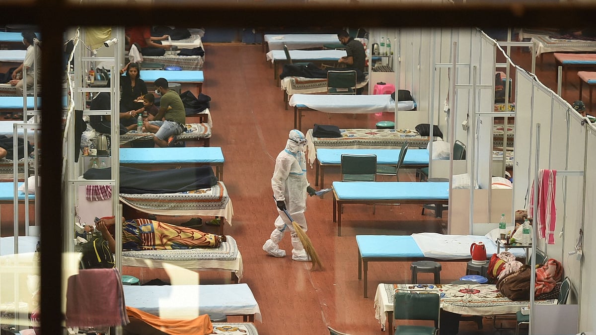 A worker wearing a PPE kit cleans a ward of CWG COVID-19 care centre in Delhi.