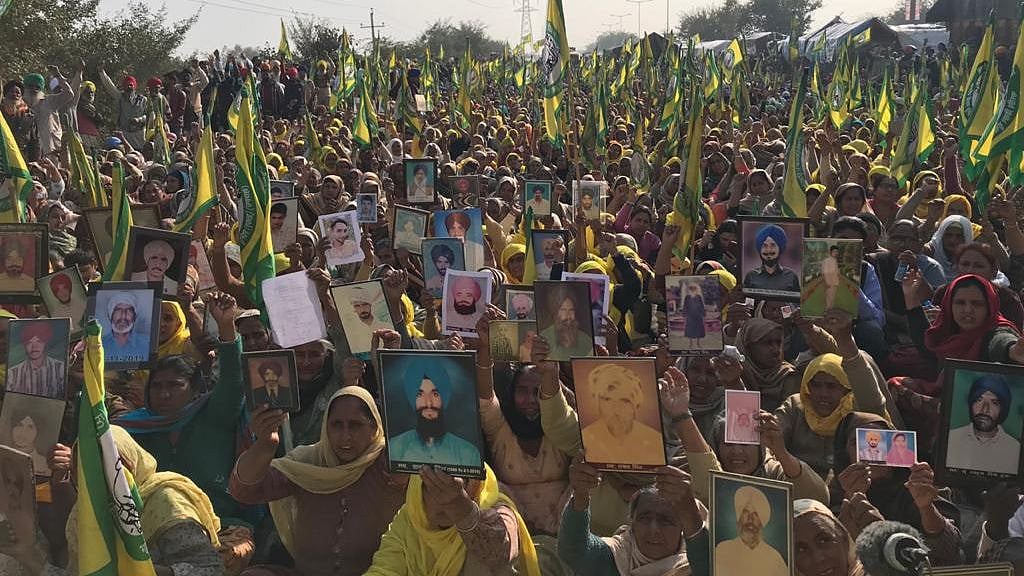 Widows and mothers with portraits of their kin who died by suicide, owing to farm debts, during ongoing protest against controversial farm laws.