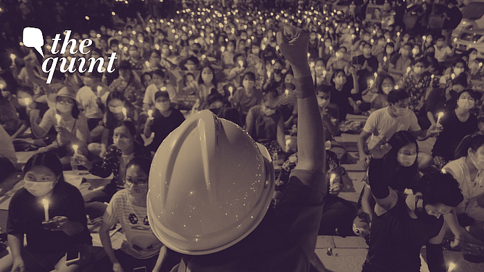 An anti-coup protestor raises his hand with clenched fist in front of a crowd during a candlelight night rally in Yangon, Myanmar on Sunday, 14 March.
