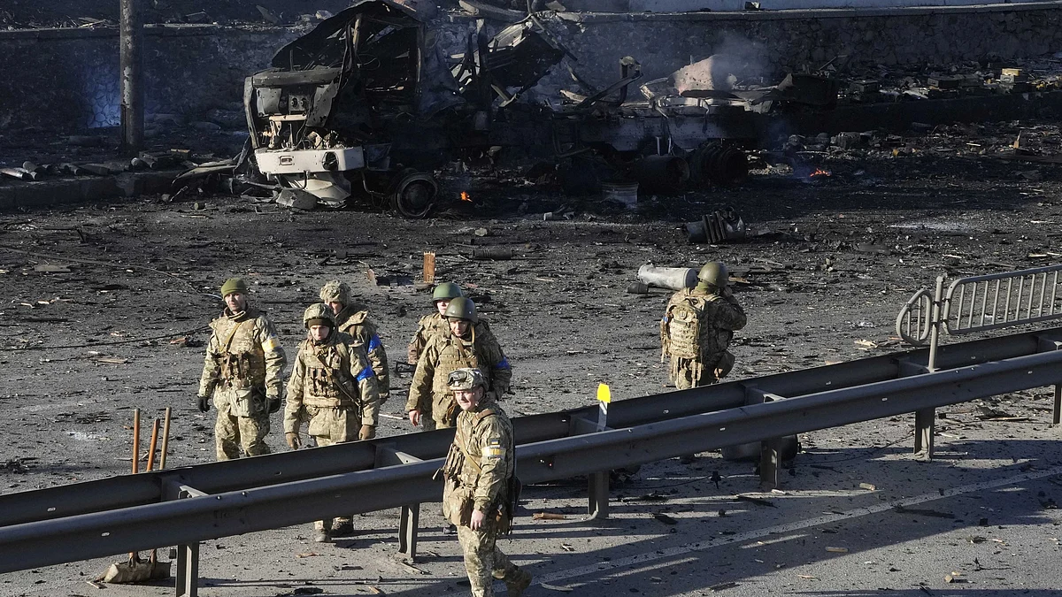 <div class="paragraphs"><p>Ukrainian soldiers walk past debris of a burning military truck on a street in Kyiv, Ukraine, Saturday, 26 February 2022.</p></div>