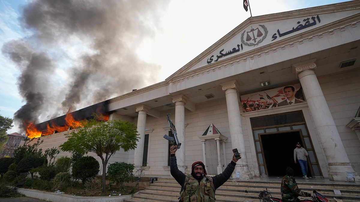 <div class="paragraphs"><p>Opposition fighters celebrate as they burn down a military court in Damascus, Syria on Sunday, 8 December.&nbsp;</p></div>