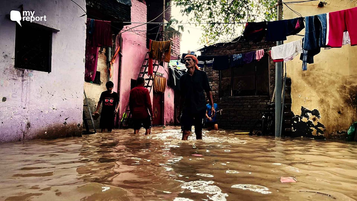 <div class="paragraphs"><p>A man wades through knee-deep water, moving belongings from his submerged home to a temporary tent in Delhi’s Yamuna Bazar.</p></div>