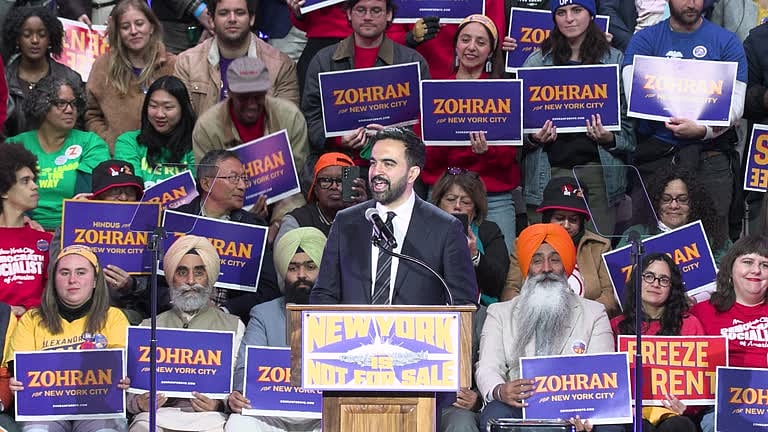 <div class="paragraphs"><p>Zohran Mamdani giving a speech at an event recently with members of the Indian American community in the background. </p></div>