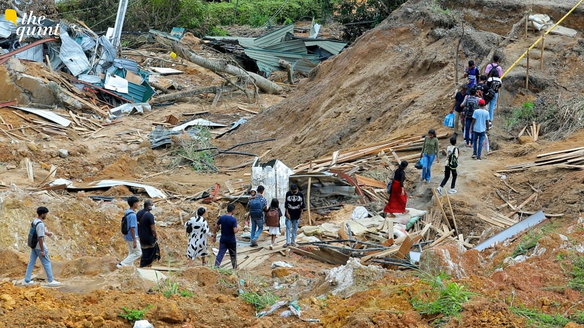 <div class="paragraphs"><p>People walk past damaged houses following a landslide in Ulapane village in Kandy, Sri Lanka.</p></div>