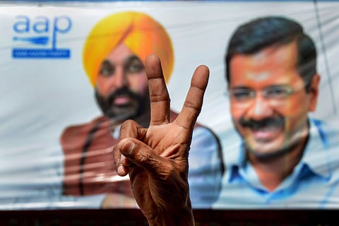 An Aam Aadmi Party (AAP) supporter flashes the victory sign, to celebrate the party's win during the counting day of Punjab Assembly elections