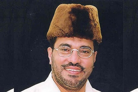 A man in a cone shaped felt cap and rimless glasses