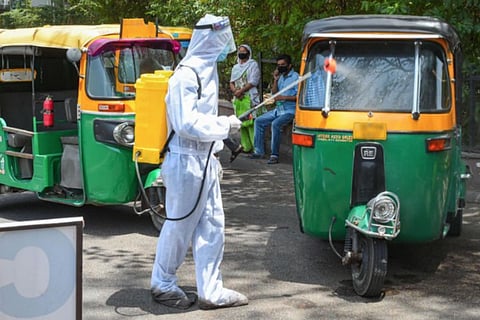 Health worker sanitizing an auto rickshaw