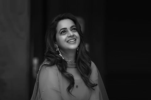 Actor Bhavana in black and white photo looking up and smiling