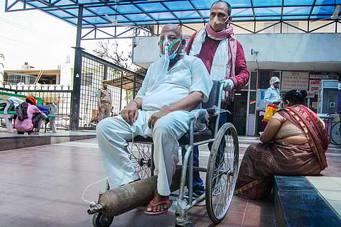 A Covid-19 positive on oxygen support waits to be admitted in a hospital