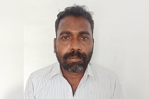 Accused Muthukumar wearing white shirt looking at camera