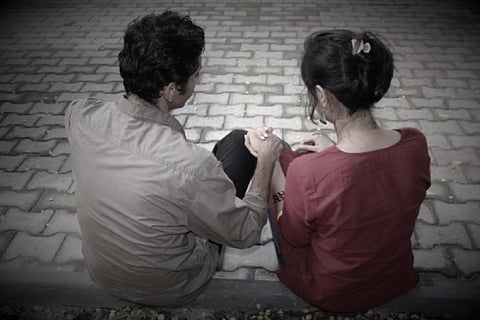 Two persons sitting on a pavement