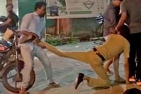 A police personnel being dragged on the road