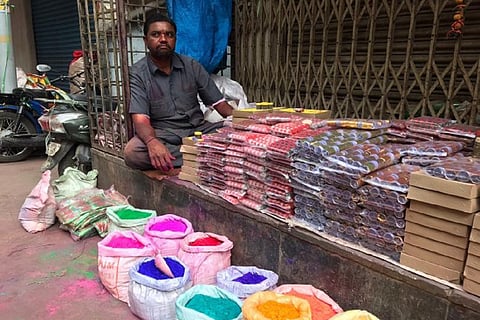 A man selling Holi colours in a street