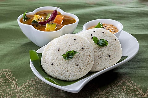 A representative image of a plate with two idlis, chutney and sambar