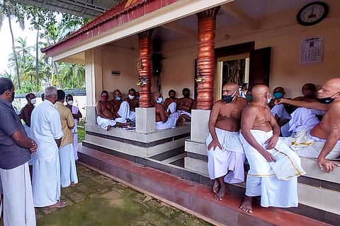 A group of men sit inside the court of an ancient Kerala temple