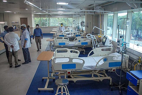 Empty hospital beds with doctors in masks standing nearby